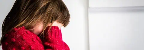 Meisje met rode trui en hand voor ogen